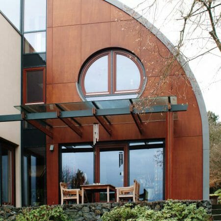 Die ungewöhnliche Hausform wird durch die individuell angefertigten Holzfenster unterstrichen.