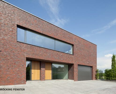 Die von BRÖCKING FENSTER gefertigten Haustüren aus eichenholz sorgen für einen angenehmen Kontrast zu den Aluminum-Fensterelementen.